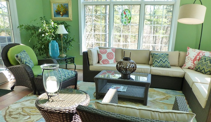 a cozy vibrant green sunroom with casual-looking furniture